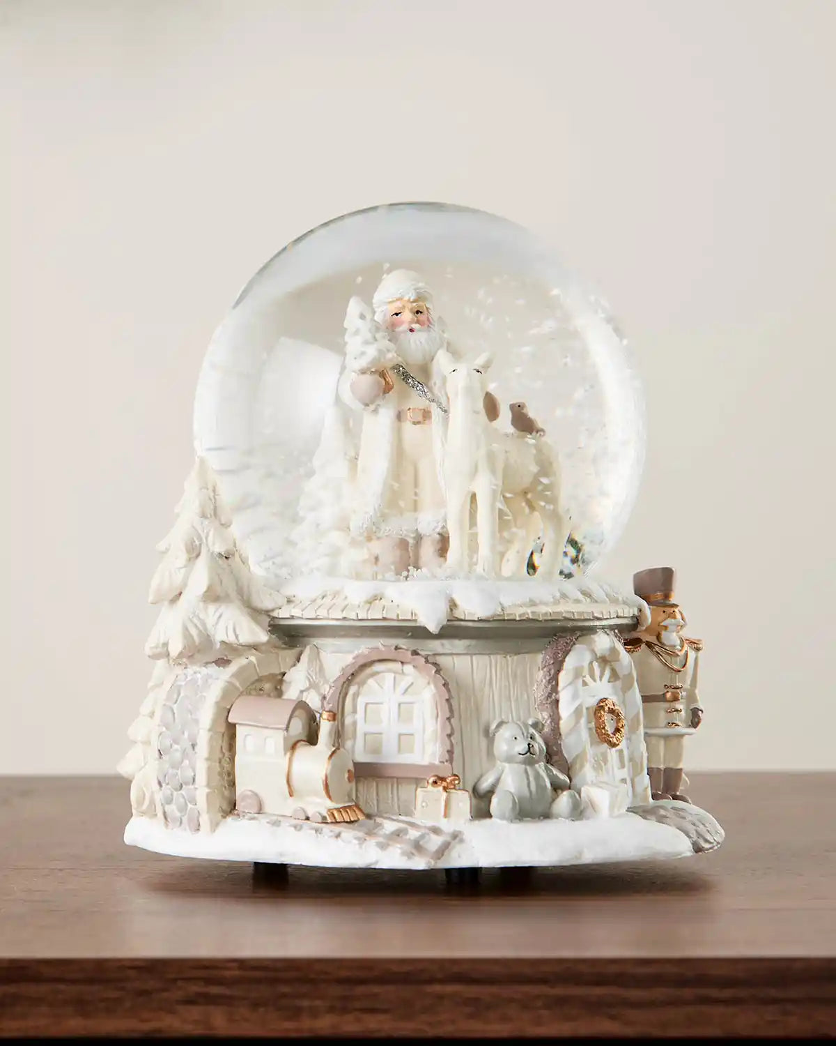 Full image of Santa snow globe on dark wood surface in front of white wall background
