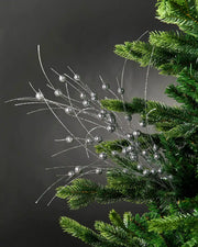 Full image of silver glitter berries spray attached to Christmas tree in front of grey wall background