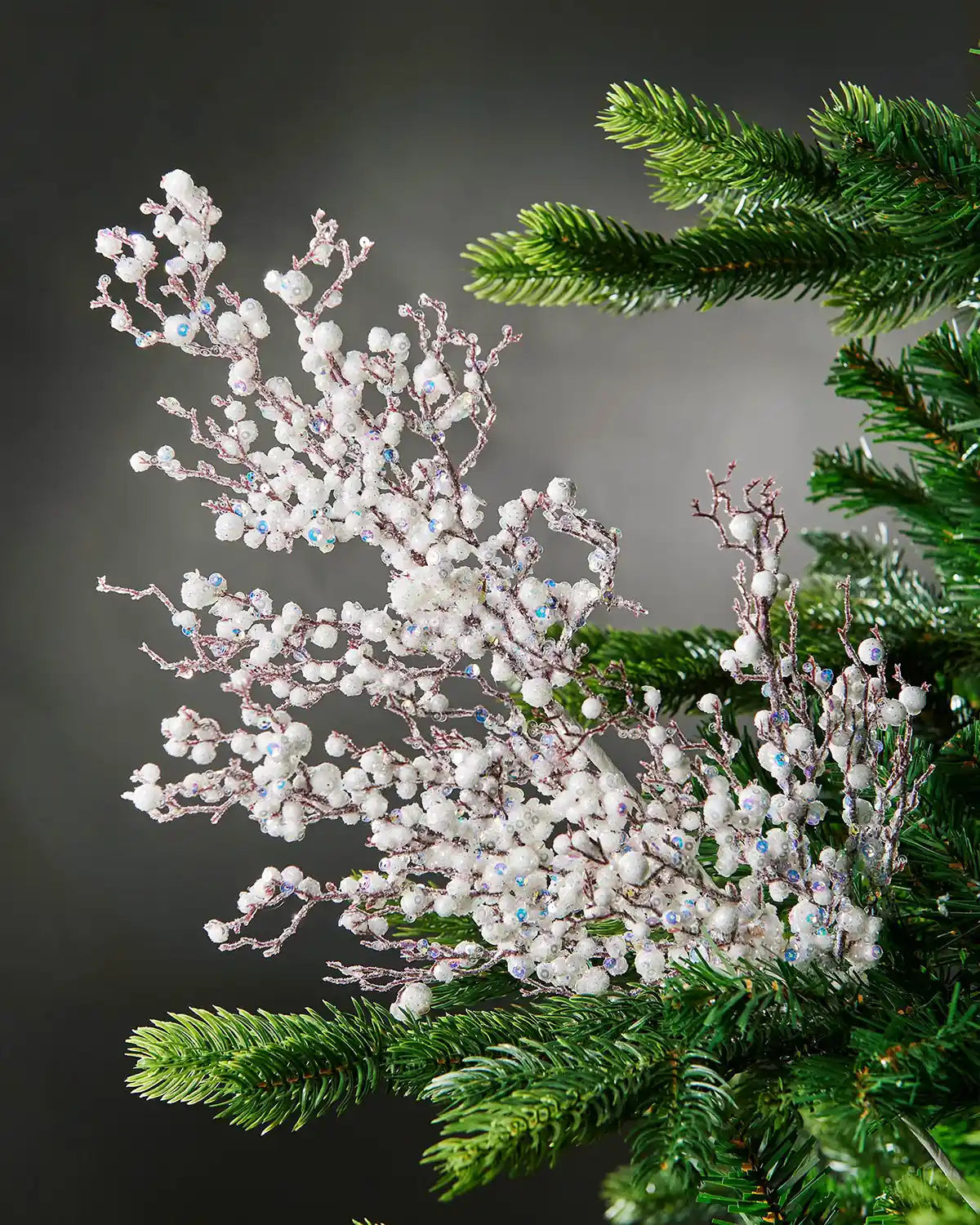 Full image of white pearls crystal spray attached to Christmas tree in front of grey wall background