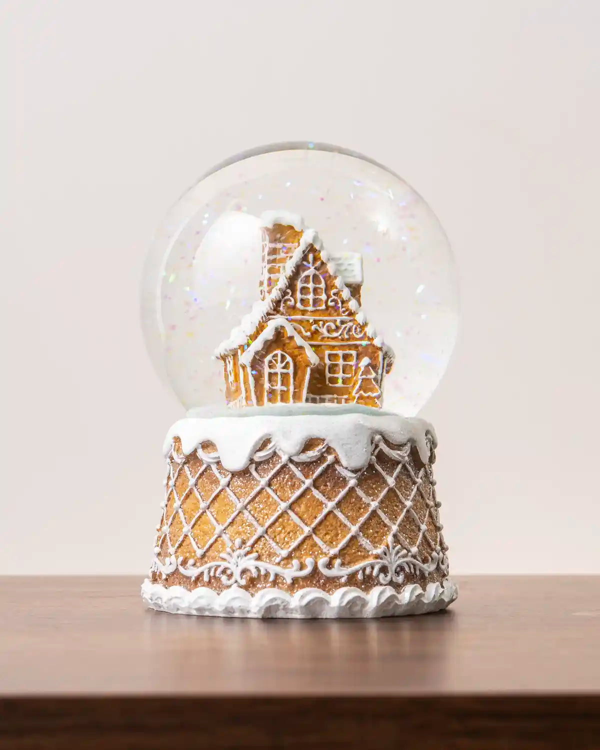 Gingerbread snow globe featuring a detailed gingerbread house inside a clear glass dome, decorated with white icing