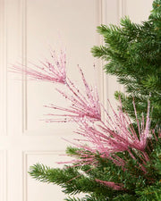 Glitter Firework Spray in Pink, featuring multiple thin, glitter-covered branches in a firework shape against a green Christmas tree.
