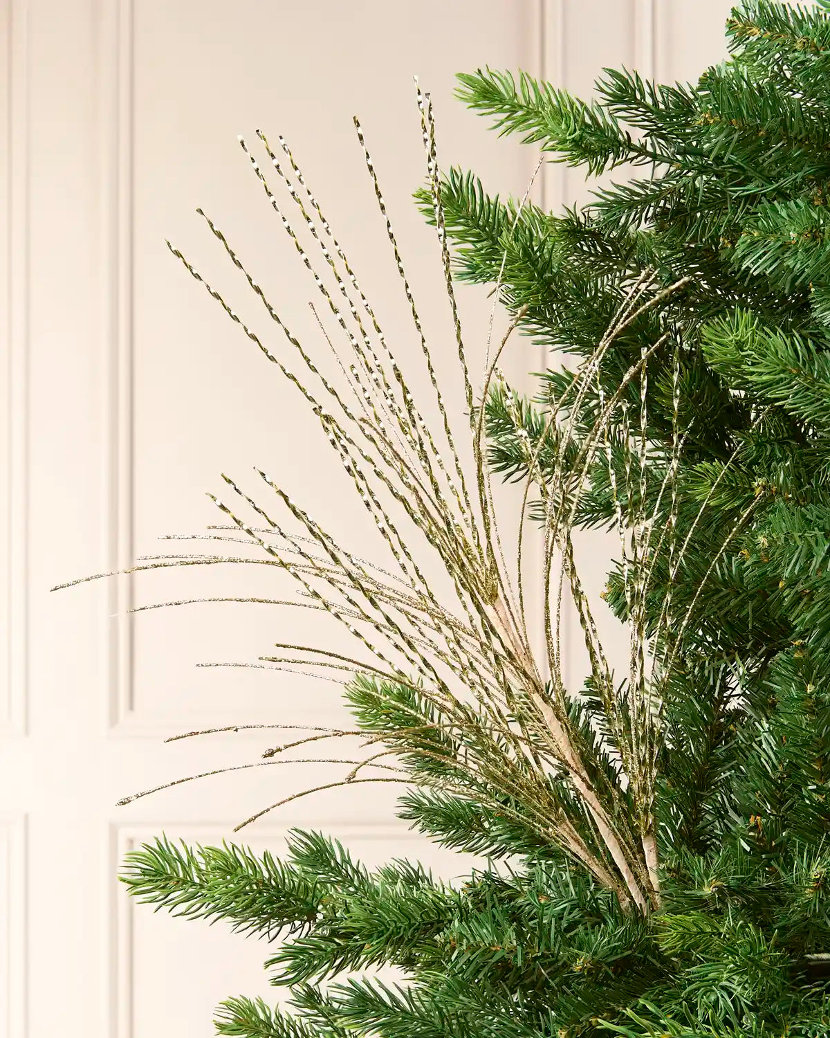 Glitter Fountain Christmas Tree Spray in gold, featuring numerous shimmering, twisted sprays fanning outward among green Christmas tree branches