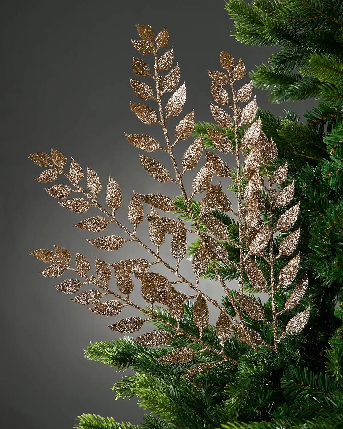 Decorative gold leaf branch on a Christmas tree against a dark background