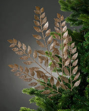 Decorative gold leaf branch on a Christmas tree against a dark background