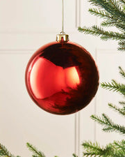 Gloss 15cm oversized bauble on a Christmas tree branch against a cream panel background