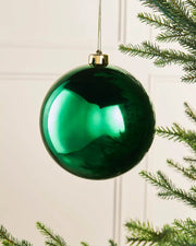 Gloss Christmas green 15cm oversized bauble on a Christmas tree branch 
