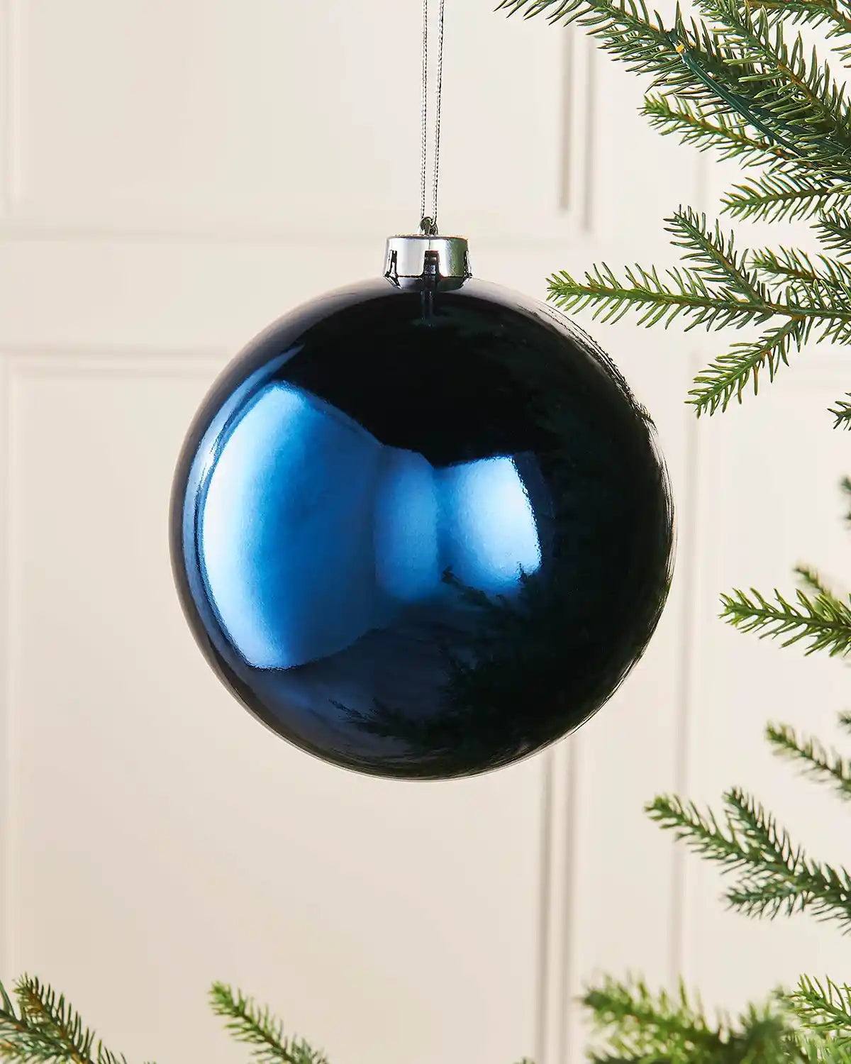 Gloss Navy blue 15cm oversized bauble on a Christmas tree branch 
