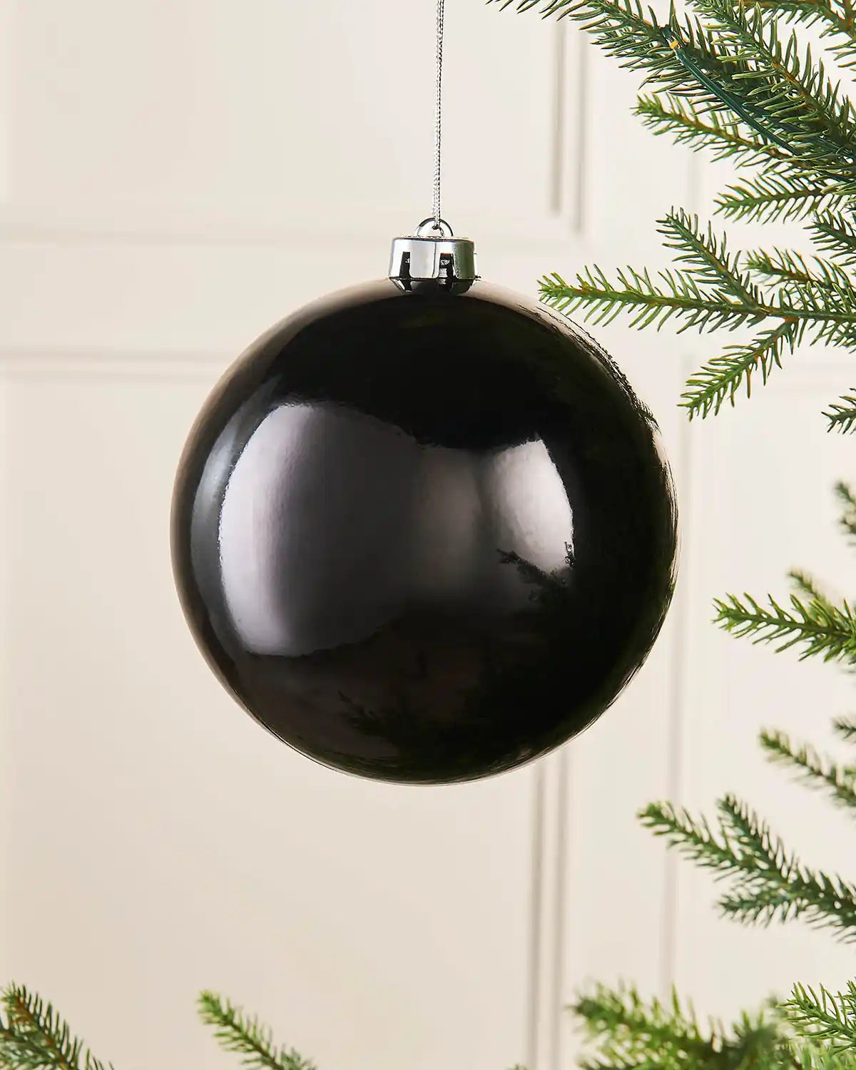 Gloss black oversized 15cm bauble on a Christmas tree branch