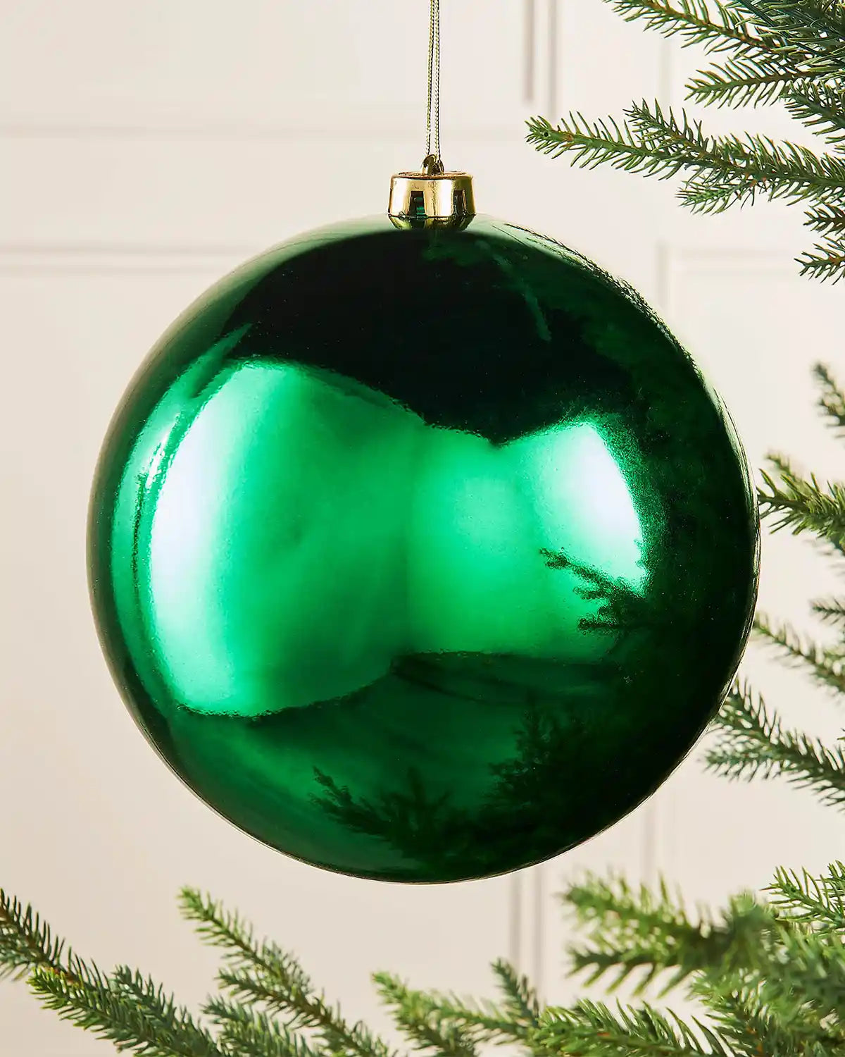 Gloss green oversized bauble on a Christmas tree branch