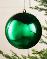 Gloss green oversized bauble on a Christmas tree branch