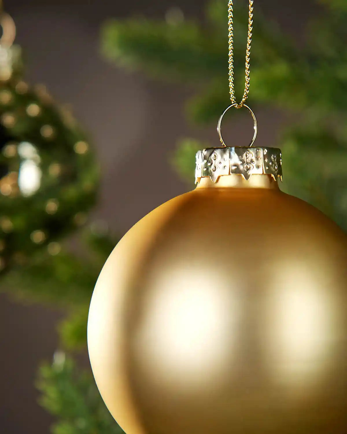 Gold Christmas baubles hanging on a tree with a blurred background