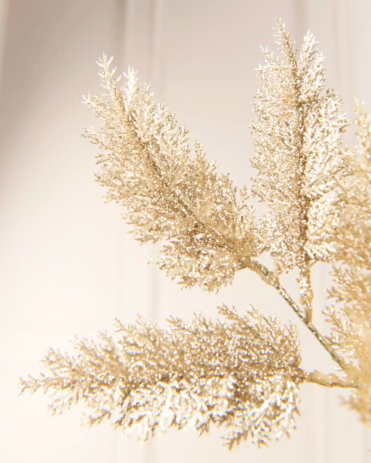 Gold Foliage Spray, glittering gold foliage on branching stems, shown in close-up to highlight its textured, shimmering leaves