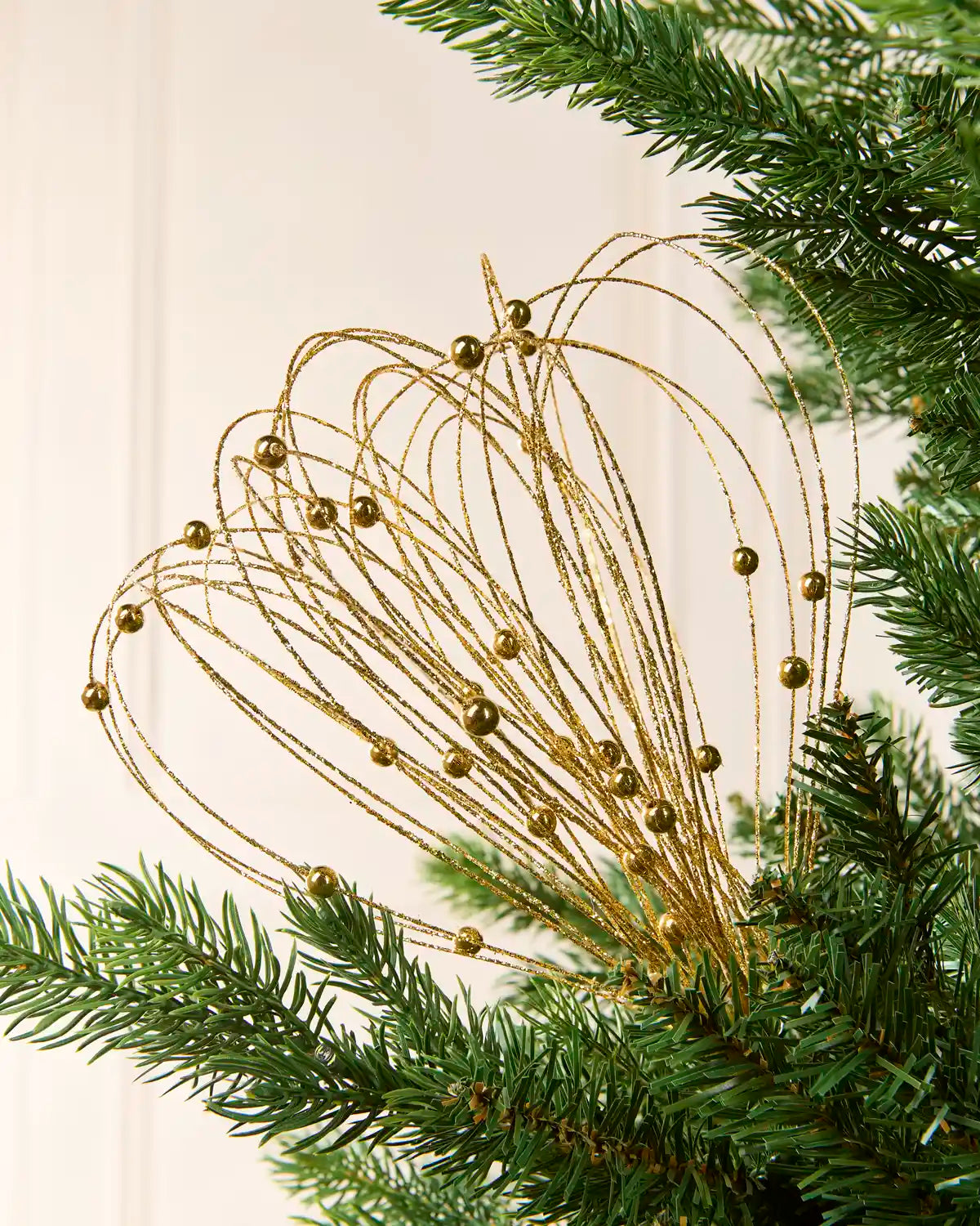 Gold Glitter Nest Christmas Tree Pick placed in green Christmas tree branches with a cream background
