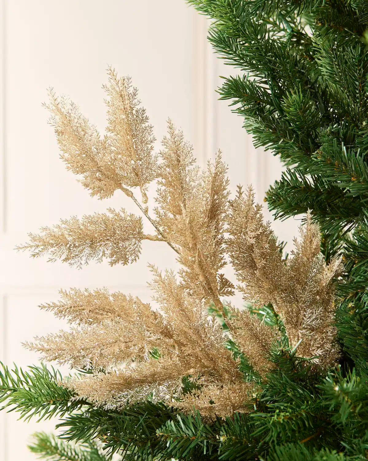 Gold Large Glitter Tip Spray arranged with Christmas tree branches with a blurred cream background