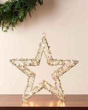 Gold and copper light up LED star on a wooden table with Wreath on wall 