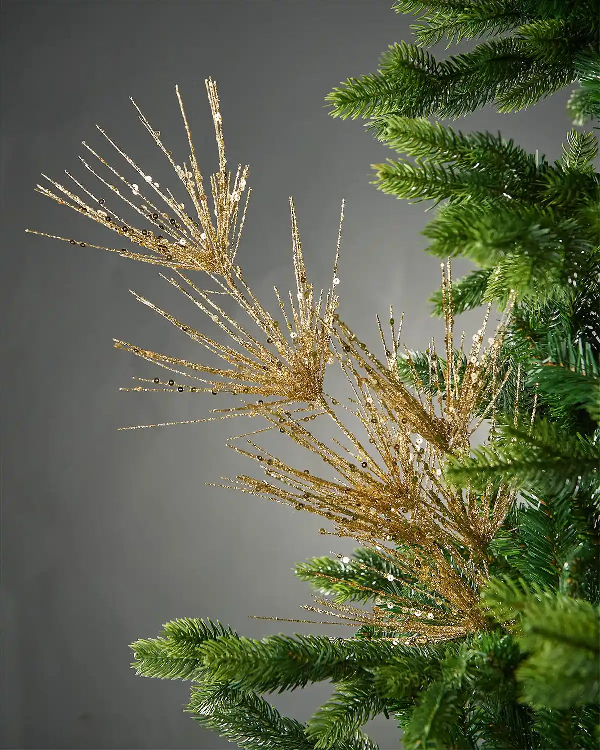 Gold glitter firework spray in Christmas tree in front of grey background
