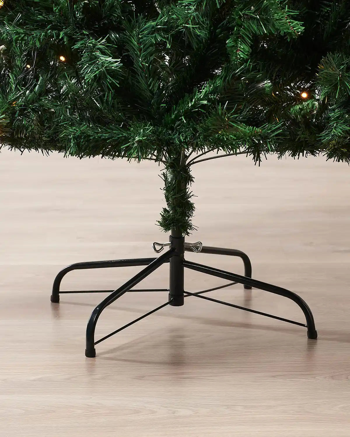 Green 6ft artificial Christmas tree with black stand on a wooden floor.