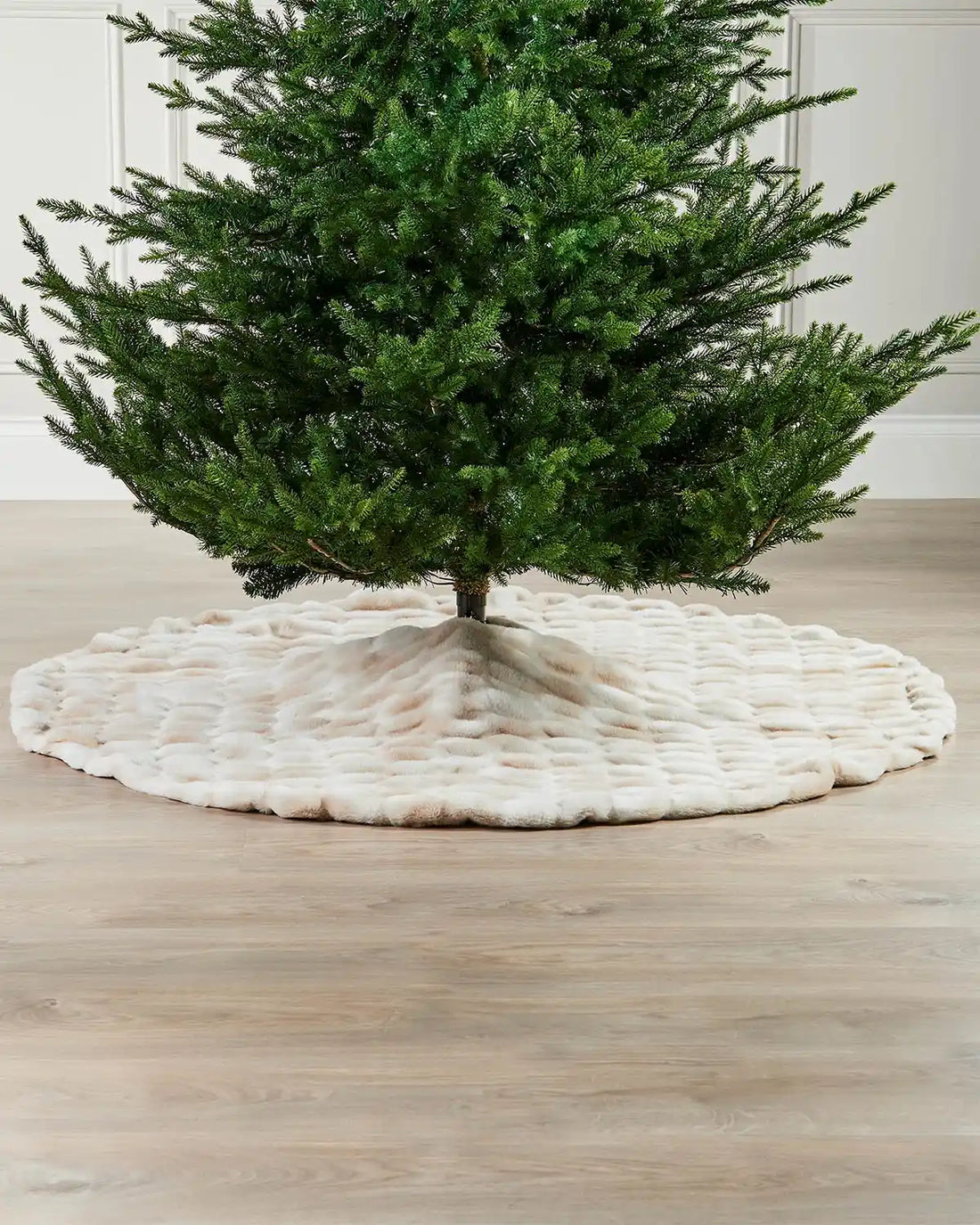Green Christmas tree on a white and beige textured base against a neutral background