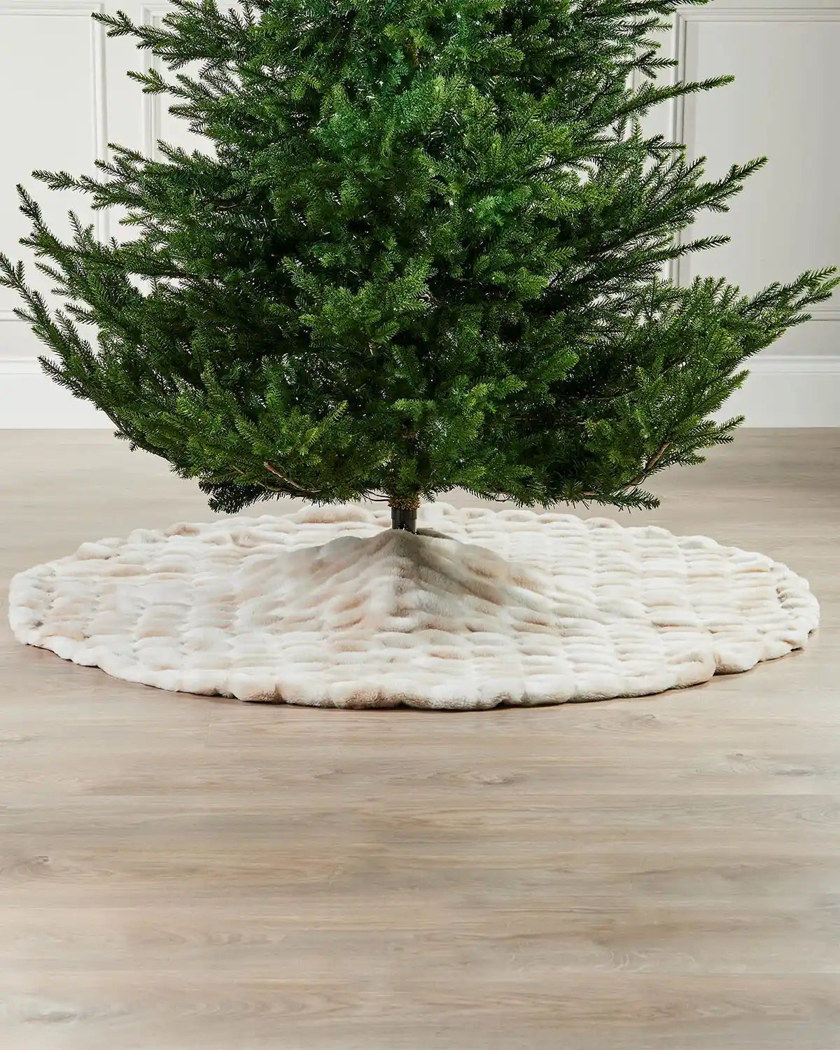 Green Christmas tree on a white and beige textured base against a neutral background