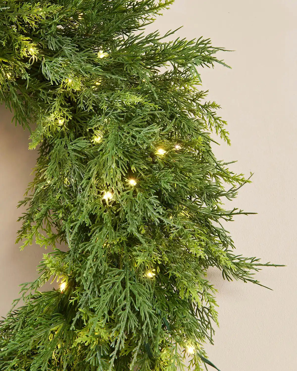 Green artificial garland with embedded lights on a neutral background