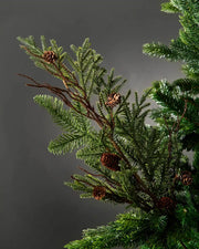 Green branch decorated with pinecones and brown branches on a Christmas tree against a grey background