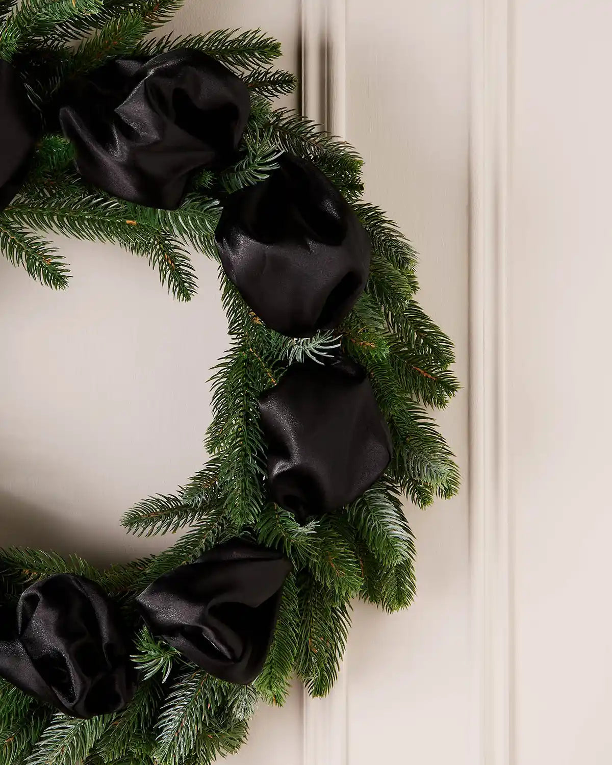 Green wreath with black ribbons on a white wall