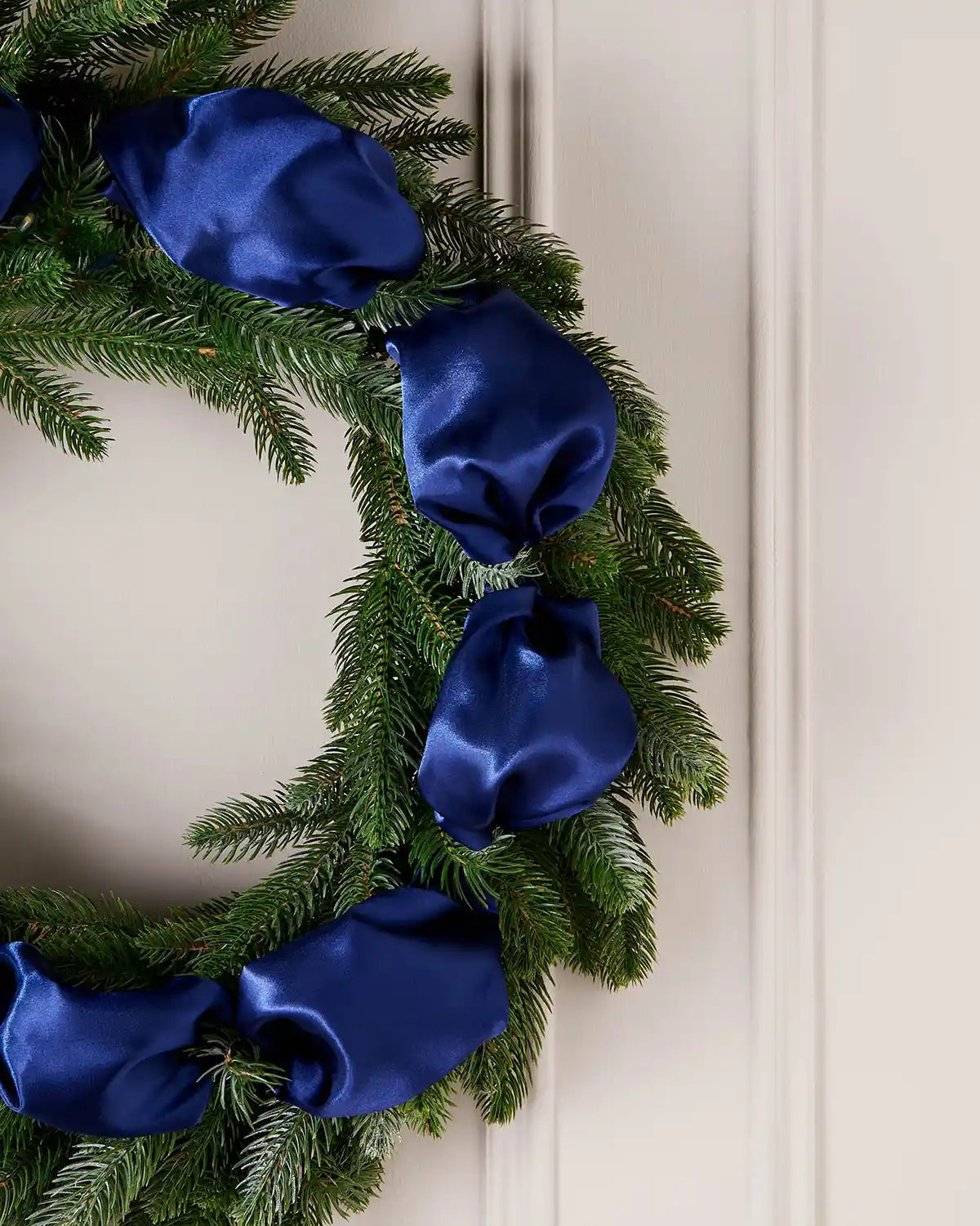 Green wreath with blue ribbons on a white door