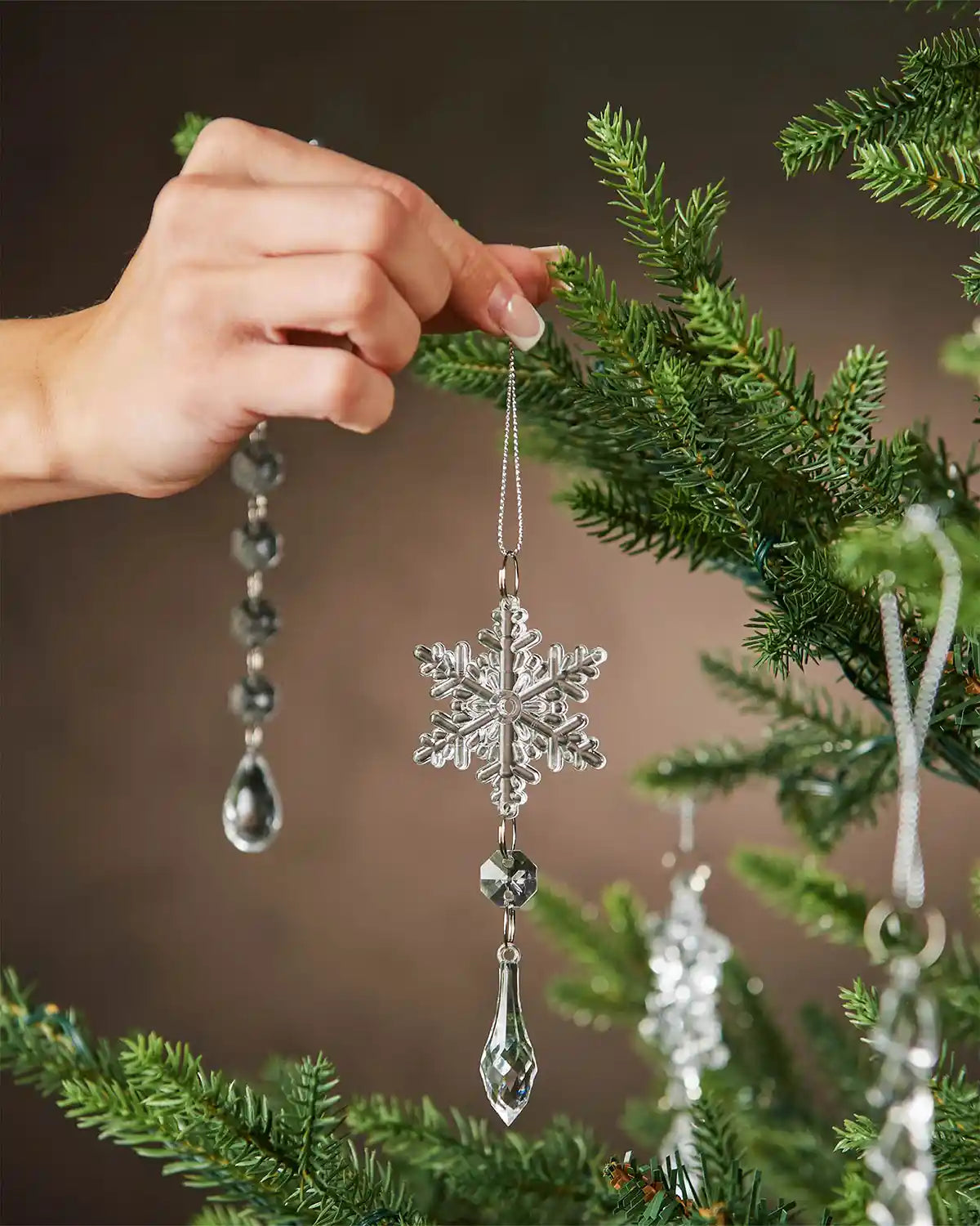Hand holding Crystal snowflake ornament hanging against a blurred natural background