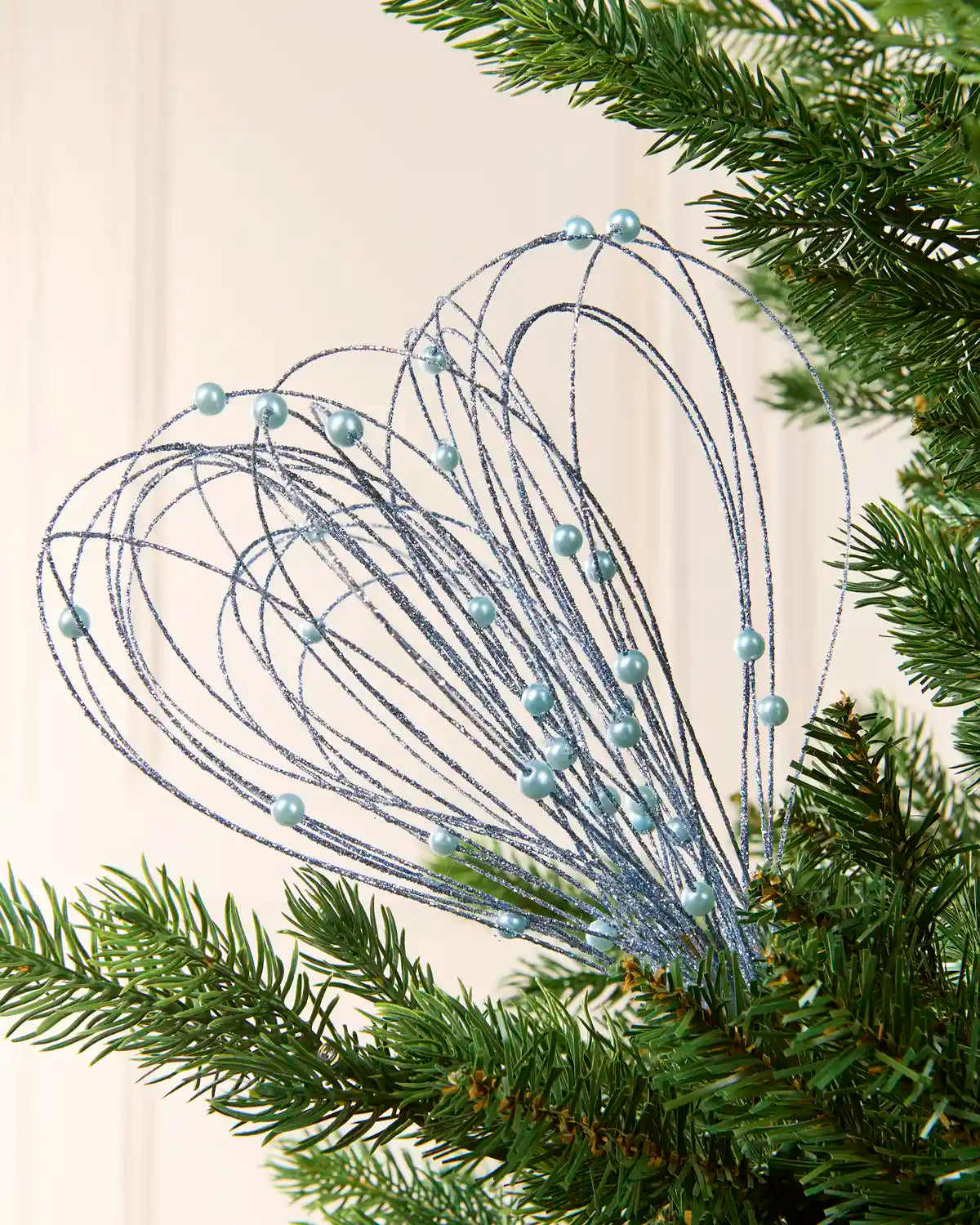 Ice Blue Glitter Nest Christmas Tree Pick placed in green Christmas tree branches with a cream background
