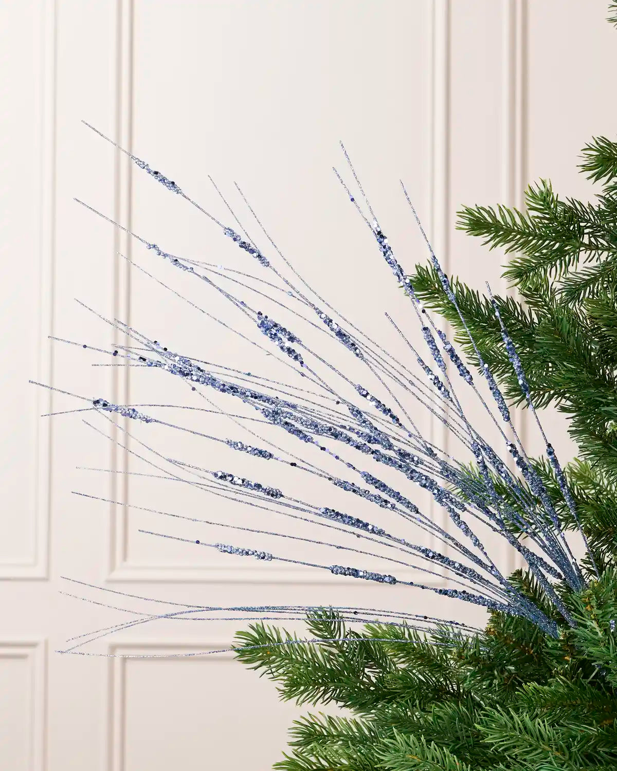 Ice Blue Glitter Wispy Spray with long, slender glitter-covered stems arranged in a fan shape on a Christmas tree
