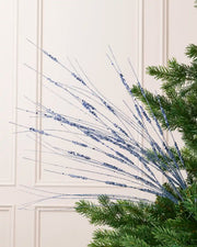 Ice Blue Glitter Wispy Spray with long, slender glitter-covered stems arranged in a fan shape on a Christmas tree

