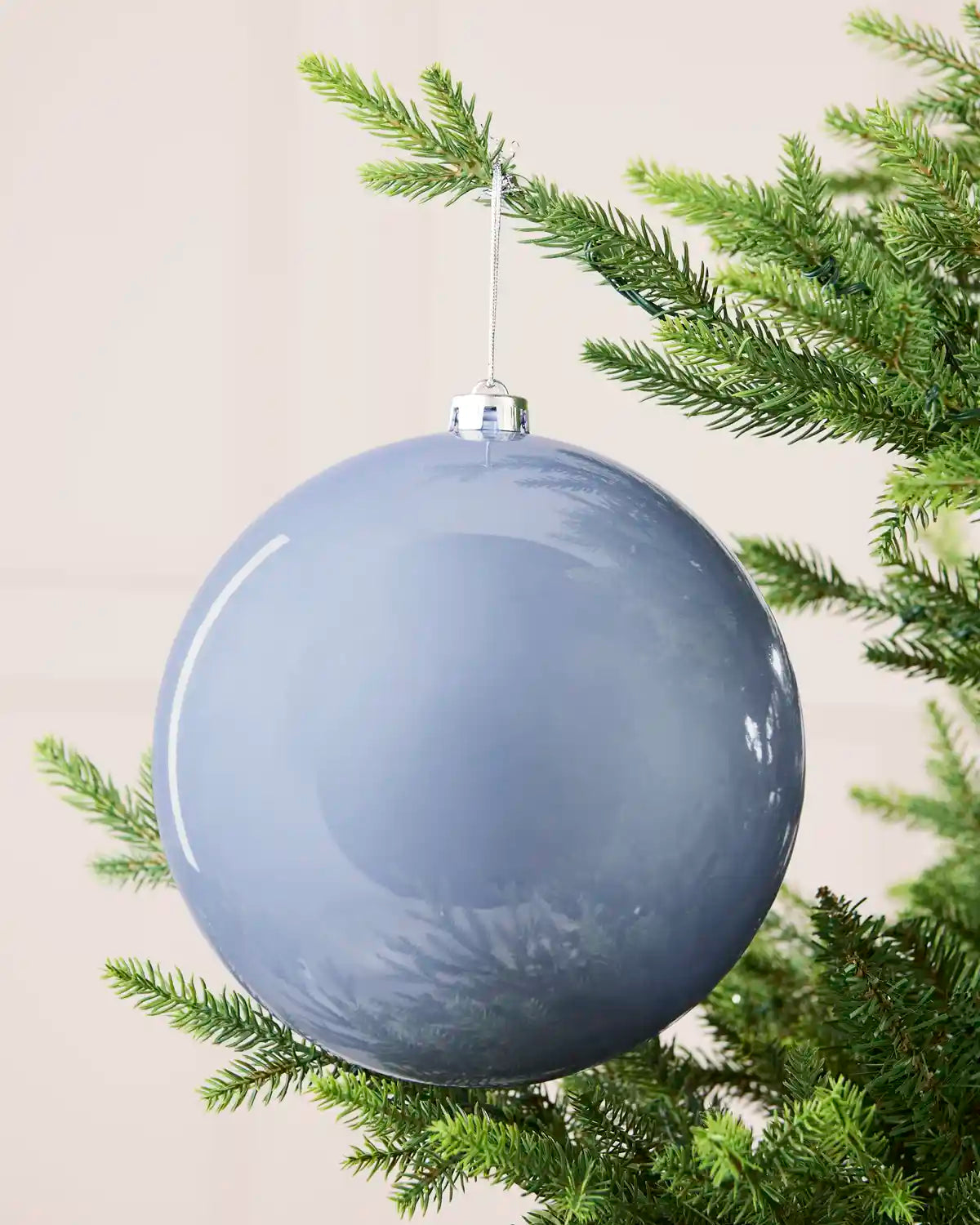 Ice blue 20 cm oversized shiny shatterproof bauble hanging on a Christmas tree with a silver cap and matching string.
