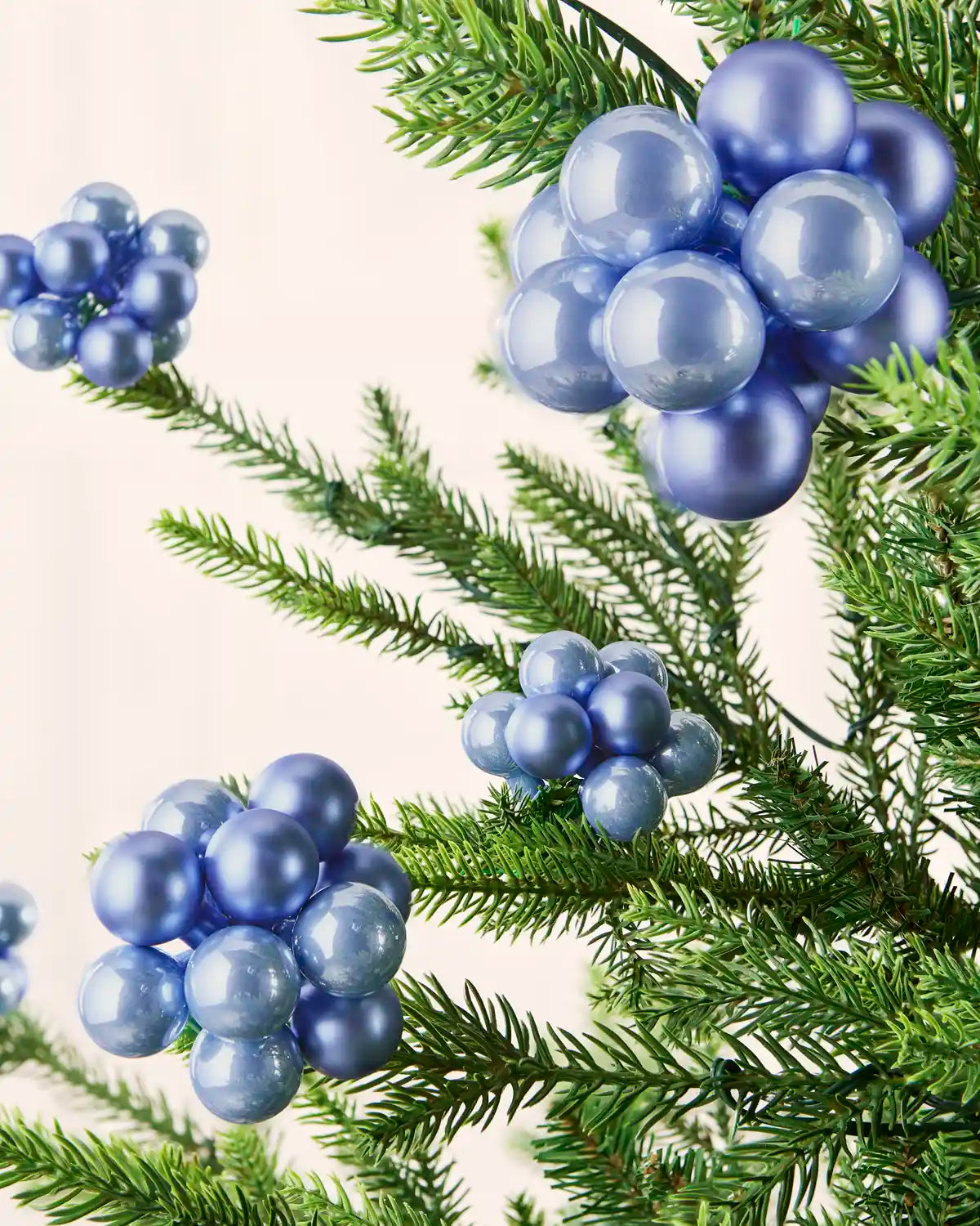 Ice blue berry cluster baubles with mixed shiny and matt glass finishes displayed on Christmas branches.
