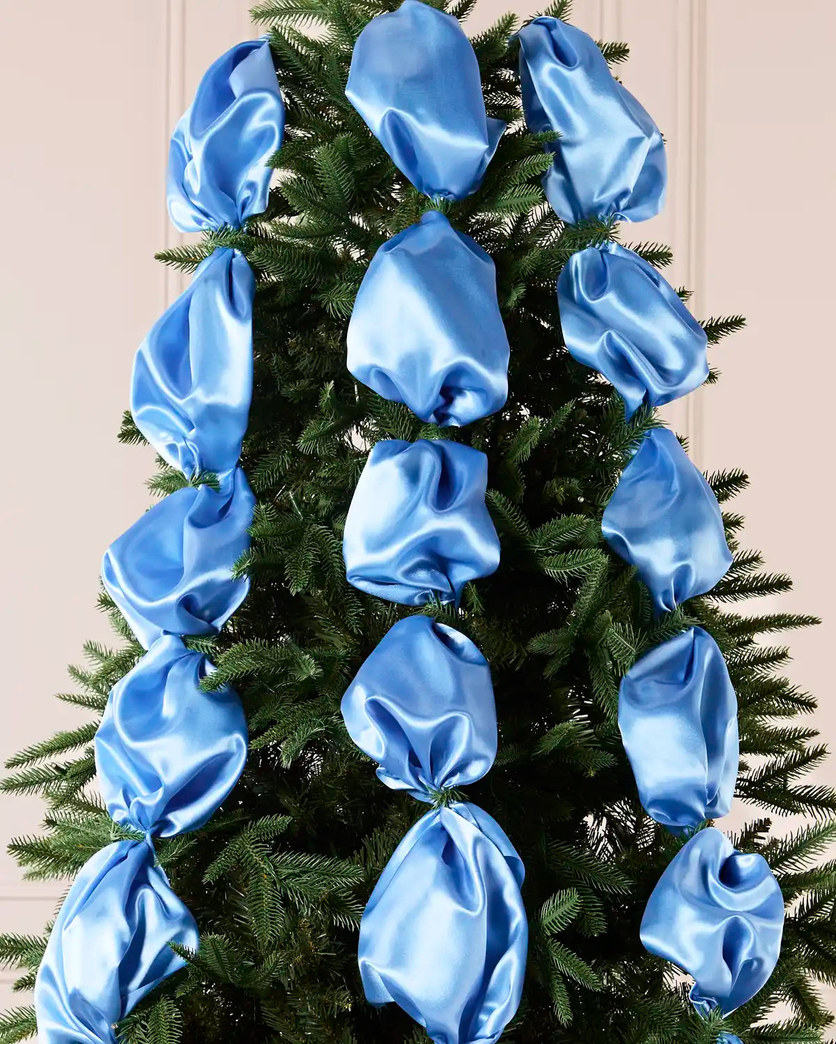 Ice blue satin ribbon draped and arranged on a green Christmas tree.