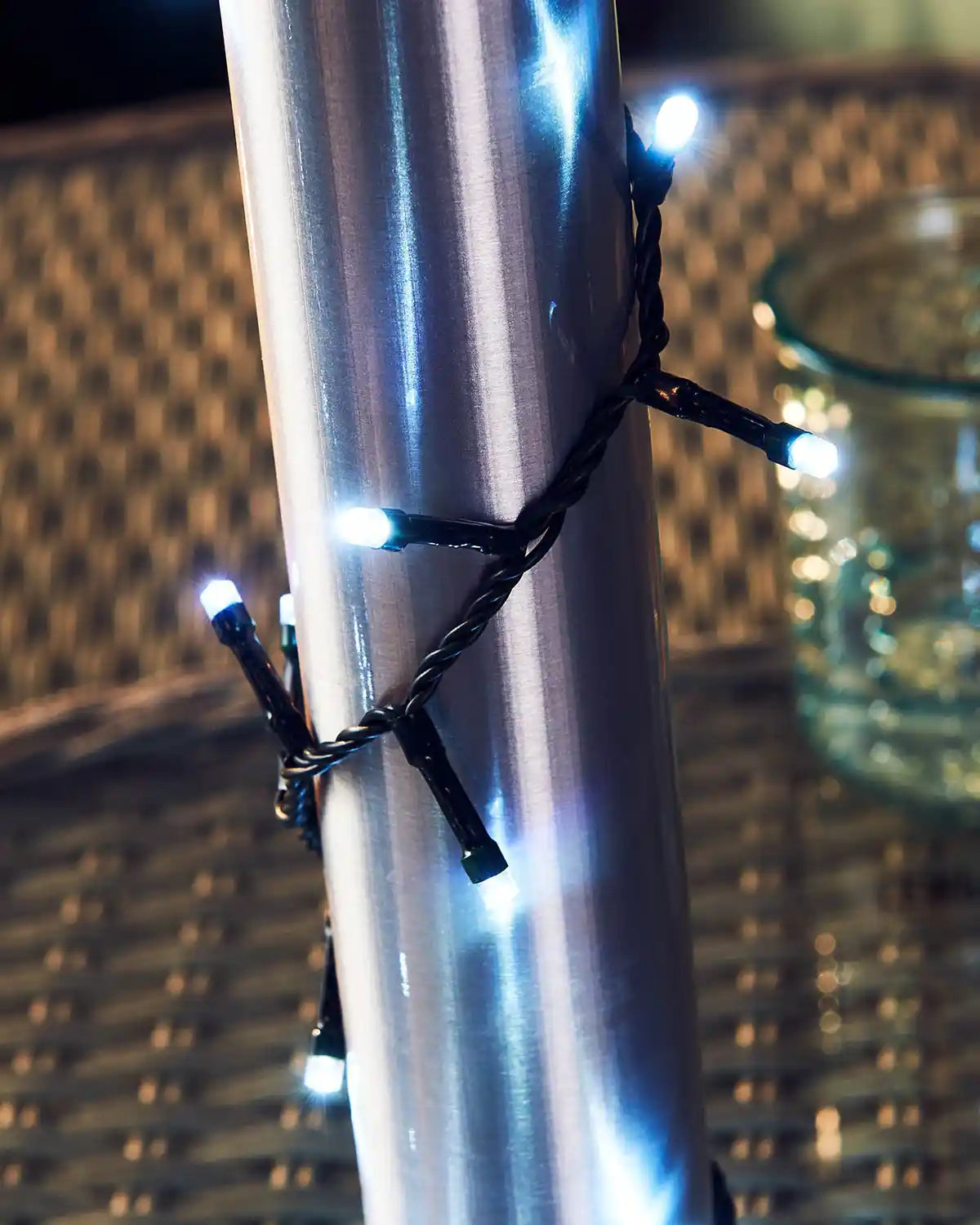 Ice white String lights wrapped around a metallic pole with a blurred background