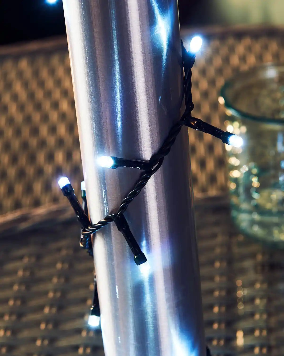 Ice white String lights wrapped around a metallic pole with a blurred background