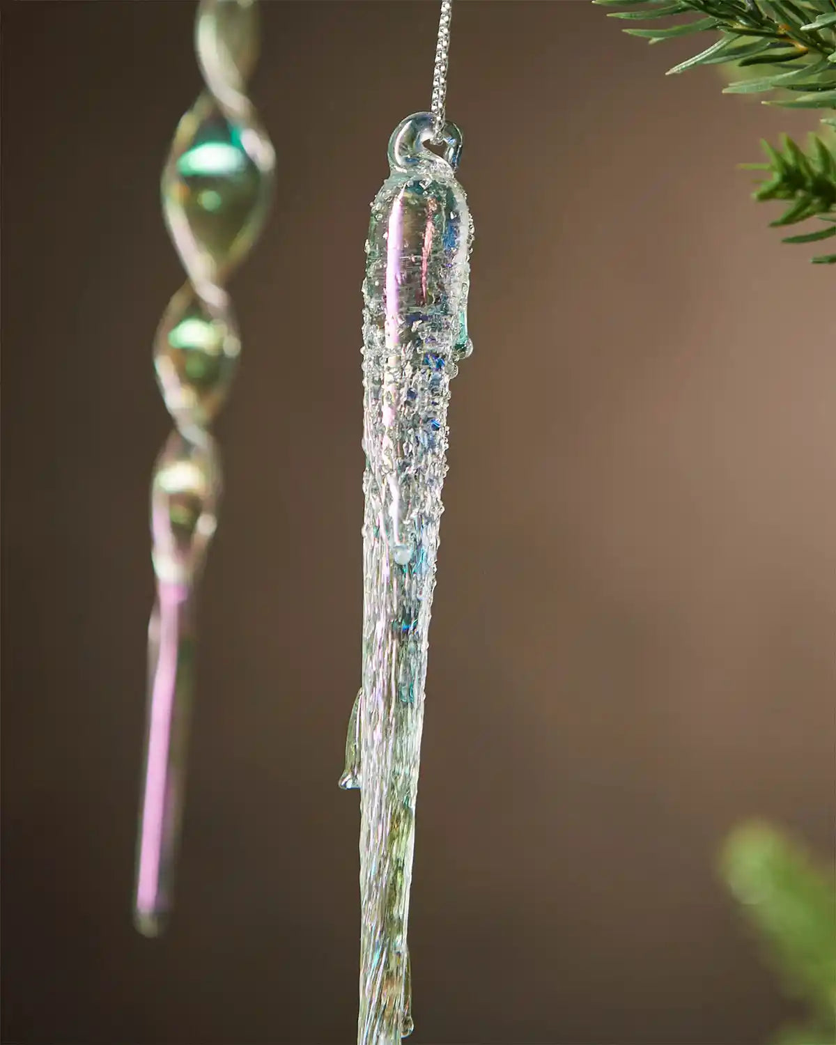 Icicle-shaped ornament hanging on a tree branch with a blurred background