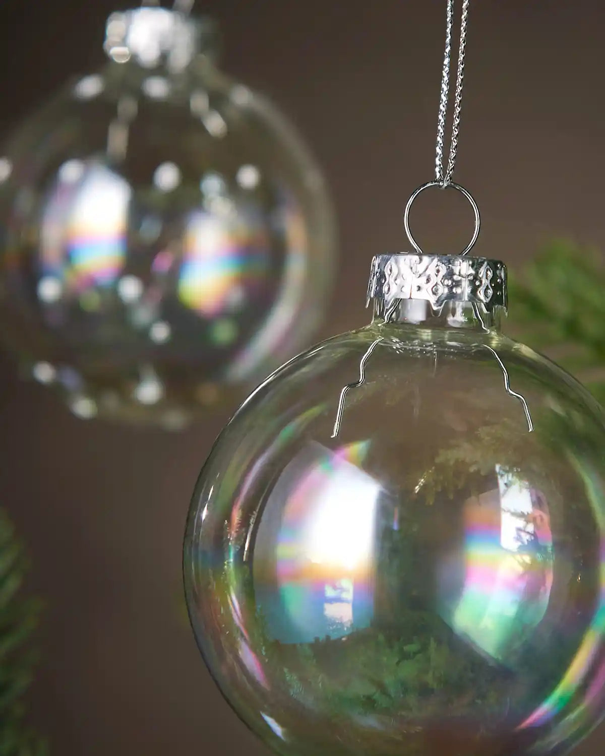 Iridescent glass Christmas ornament with rainbow reflections on a blurred green background