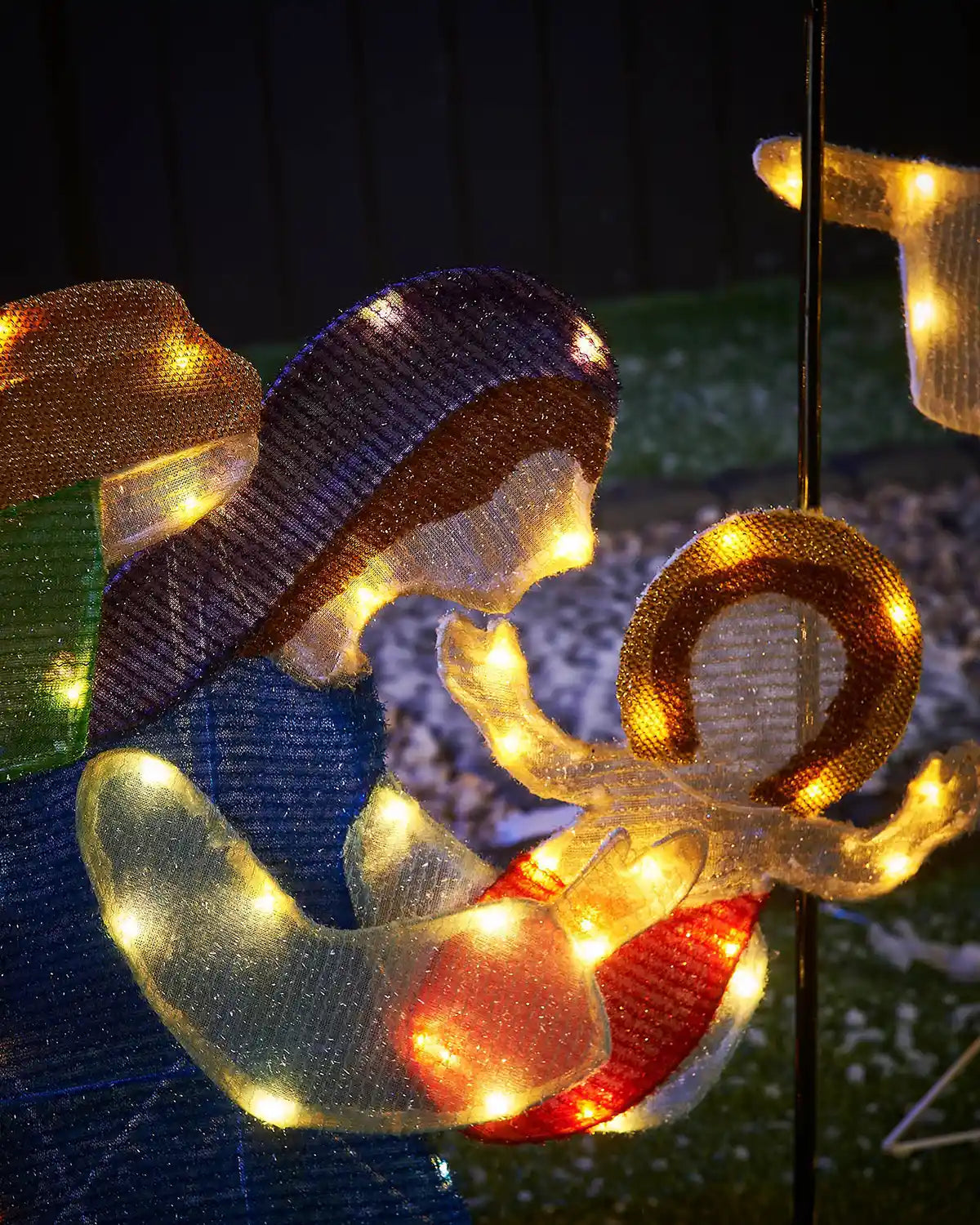 LED Mary holding LED baby Jesus against snowy grass and dark background