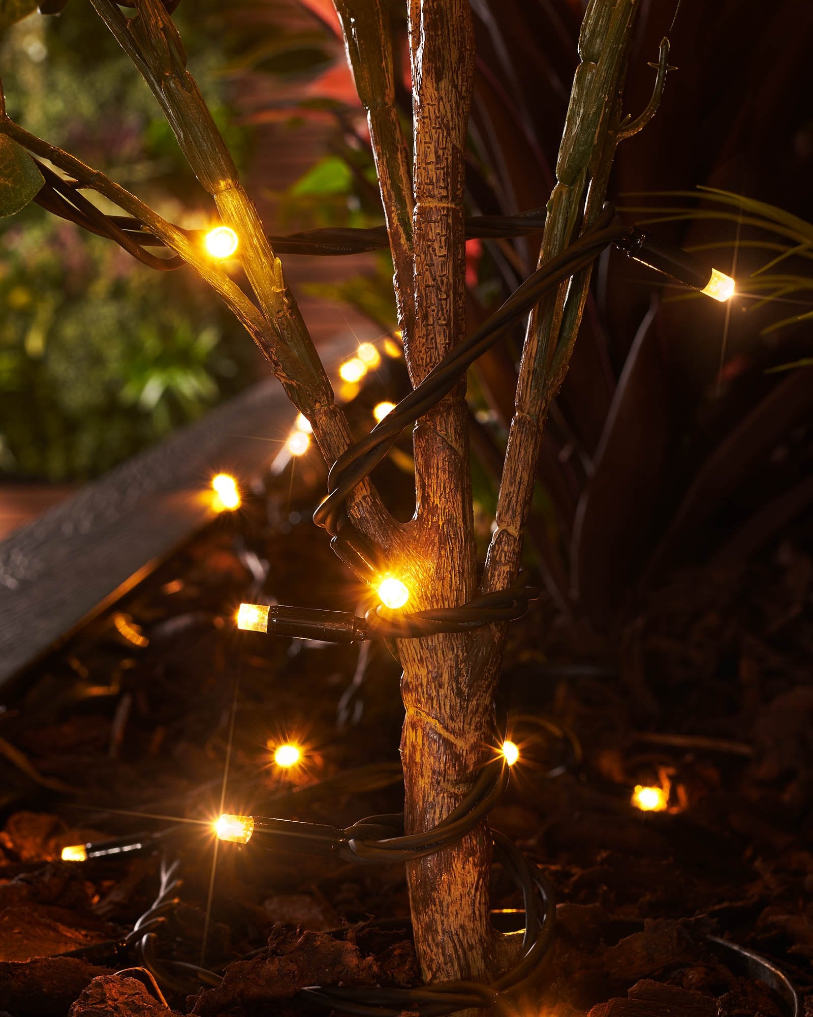 Close-up of warm white LED Christmas string lights with a focus on the twinkle or flashing feature, displayed against a blurred background of similar lights creating a cozy, festive atmosphere.