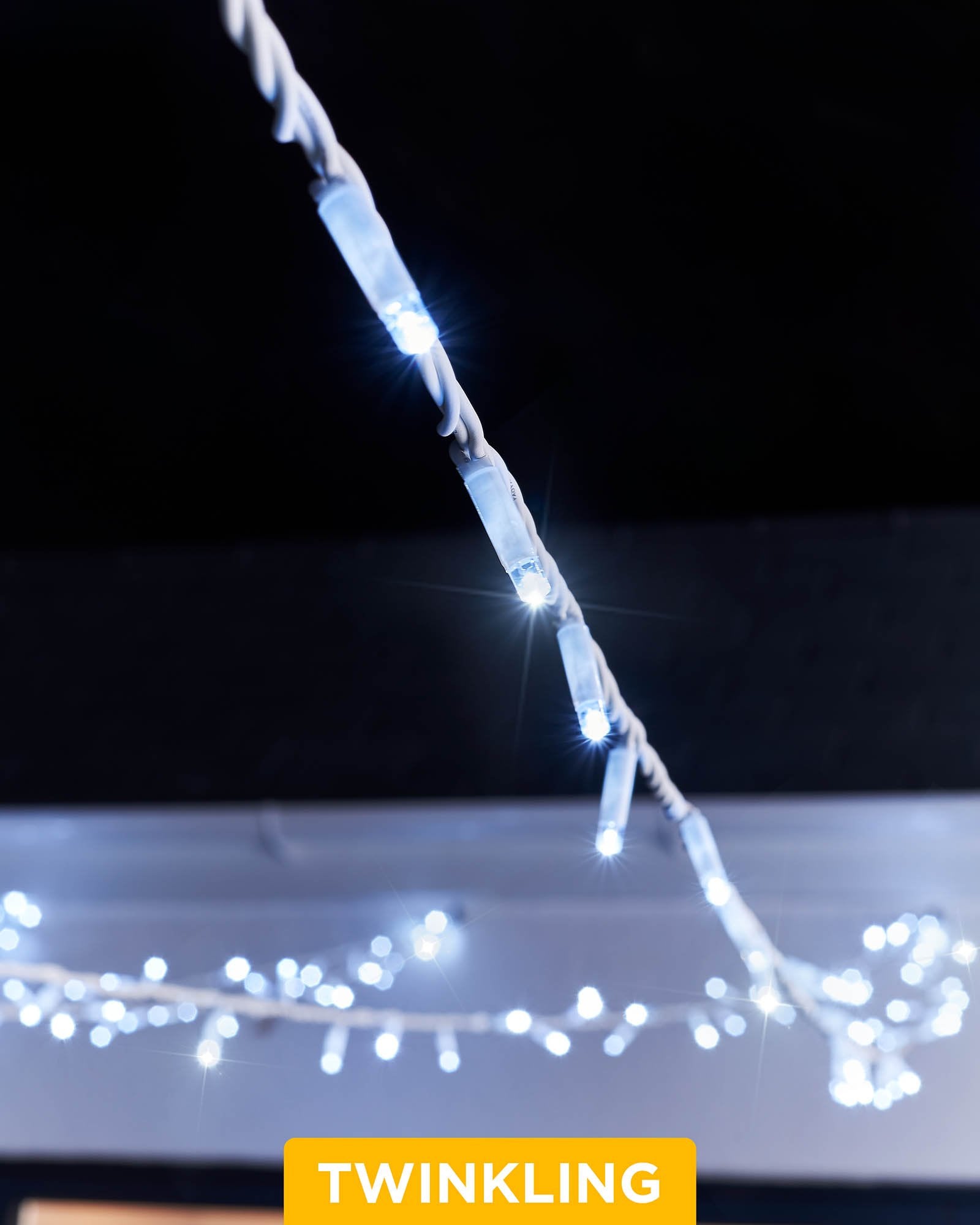 A close-up of white LED string lights with a focus on the twinkling feature, displaying the lights in an outdoor setting.