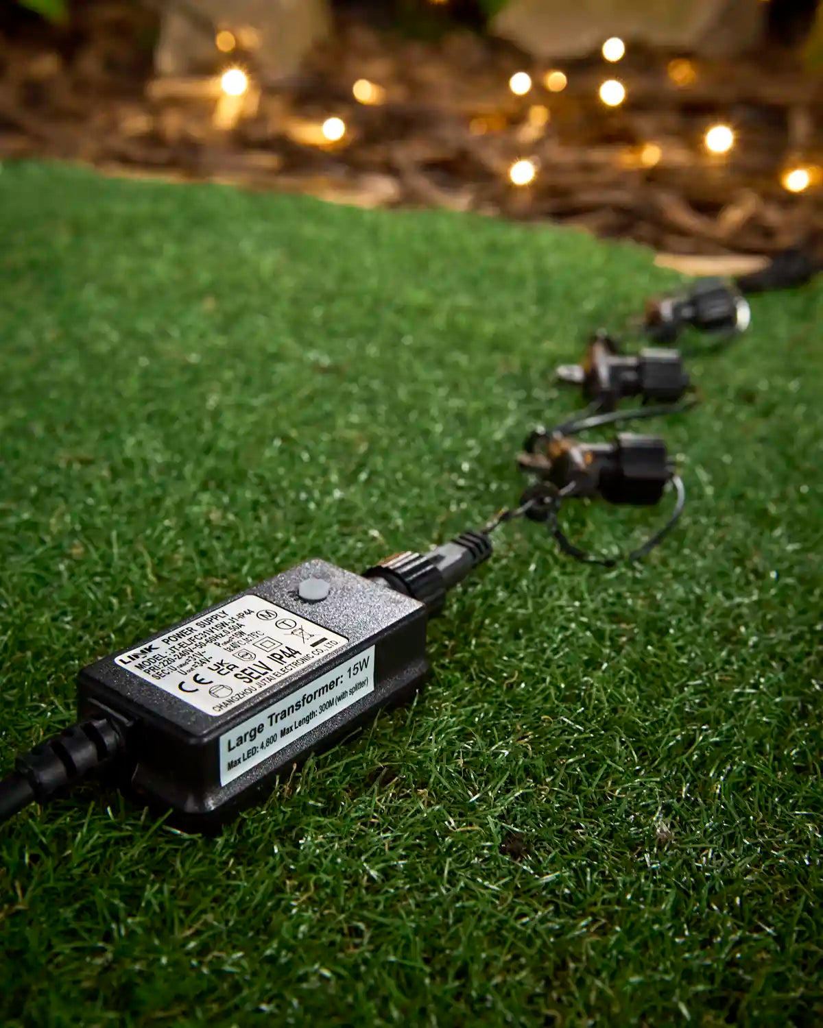 Large 15w Starter Transformer with 4 splitter connectors with blurry warm white LEDs in the background. 
