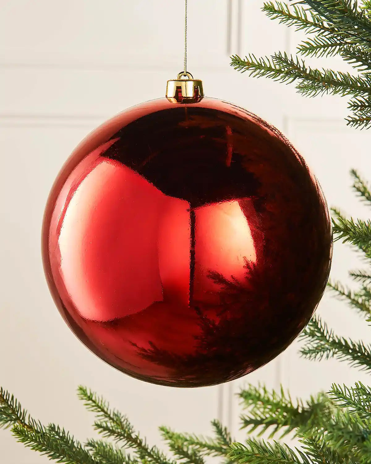 Large oversized Red gloss bauble on the tip of a Christmas tree branch