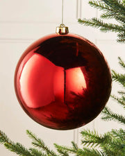 Large oversized Red gloss bauble on the tip of a Christmas tree branch