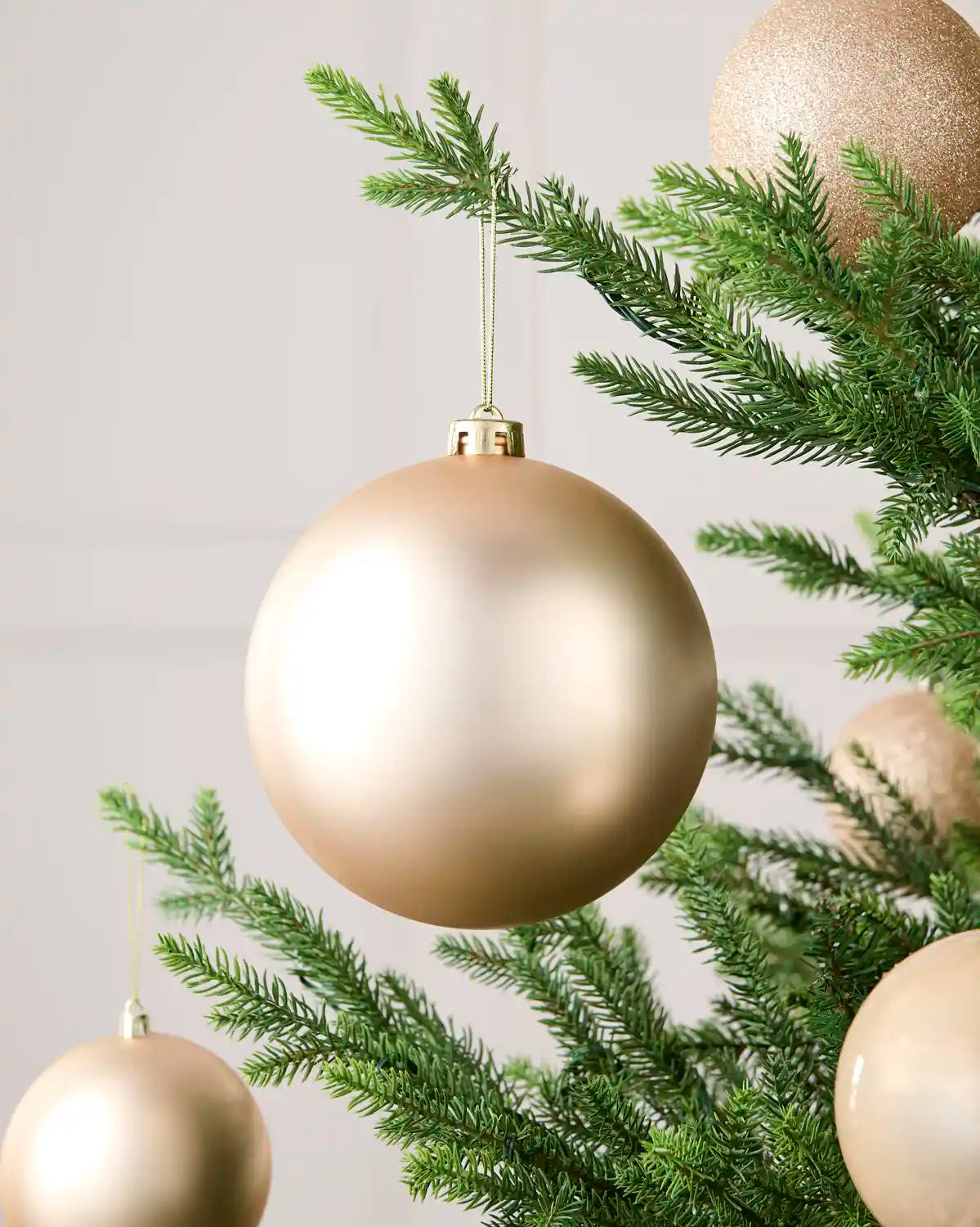 Latte 15 cm oversized matt shatterproof bauble displayed on a Christmas tree with coordinating latte baubles.
