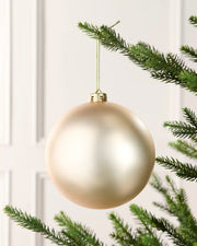 Latte 15 cm oversized matt shatterproof bauble hanging on a Christmas tree with a gold cap and matching string.
