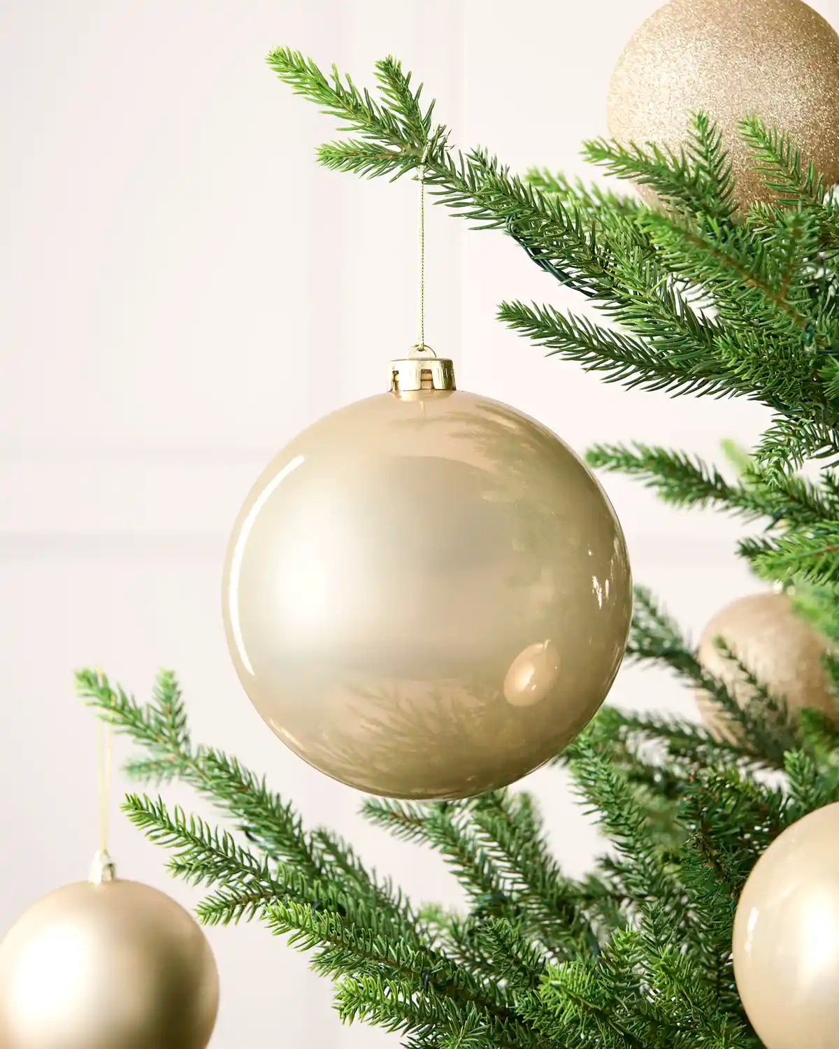 Latte 15 cm oversized shiny shatterproof bauble displayed on a Christmas tree with coordinating latte baubles.
