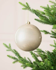 Latte 15 cm oversized shiny shatterproof bauble hanging on a Christmas tree with a gold cap and matching string.
