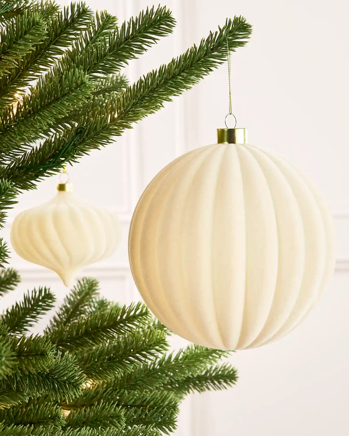 Latte 15 cm oversized velvet Ribbed bauble displayed on a Christmas tree with coordinating ornaments.
