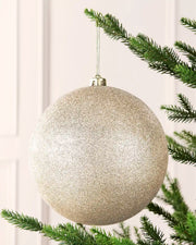 Latte 20 cm oversized glitter shatterproof bauble hanging on a Christmas tree with a gold cap and matching string.
